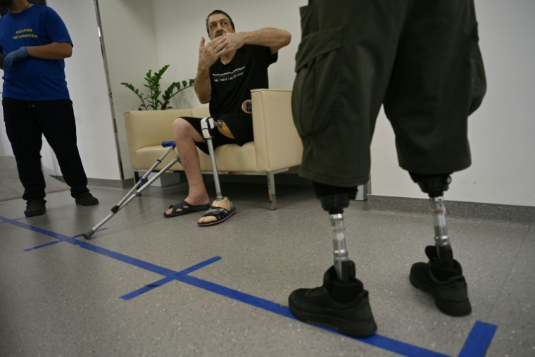 Iouriï Lavrik (au centre), 66 ans, habitant de Dnipro, s'entretient avec le personnel hospitalier au centre de rééducation de l'hôpital Metchnikov, dans la ville de Dnipro, le 8 juin 2026, dans le cadre de l'invasion russe de l'Ukraine ( AFP / Genya SAVILOV )