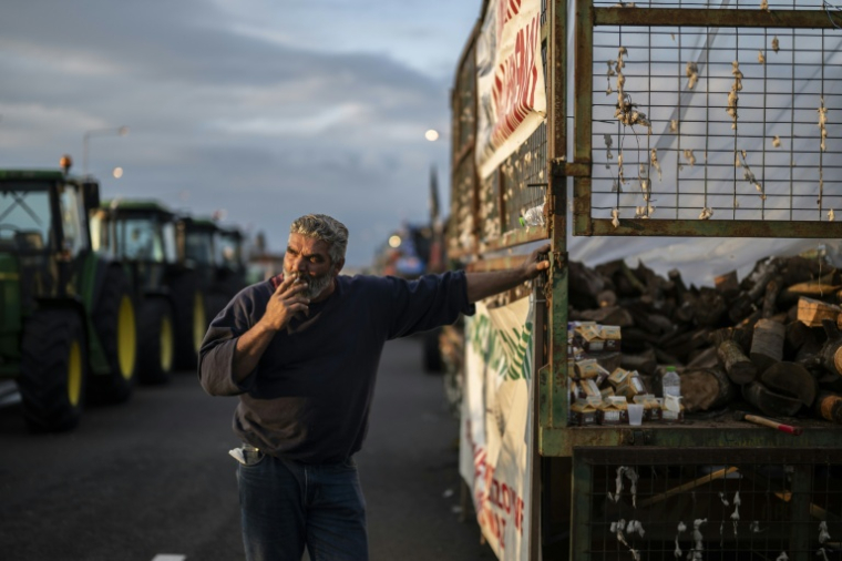 Un agriculteur attend parmi les tracteurs qui bloquent en signe de protestation une autoroute près de la ville de Karditsa, dans le centre de la Grèce, le 8 décembre 2025 ( AFP / Aris MESSINIS )