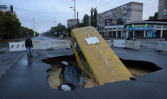 Un bus et une voiture sont visibles dans un trou sur une route à Odessa, en Ukraine, après des pluies torrentielles ayant fait au moins 9 morts, le 1er octobre 2025 ( AFP / Oleksandr GIMANOV )