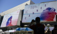 Un passant photographie les affiches de la 78e édition du Festival de Cannes devant le Palais des Festivals à Cannes, dans le sud de la France, le 12 mai 2025 ( AFP / SAMEER AL-DOUMY )