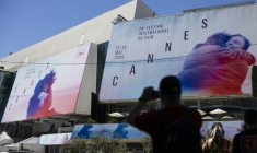 Un piéton prend une photo des affiches de la 78e édition du Festival de Cannes devant le Palais des Festivals à Cannes, dans le sud de la France, le 12 mai 2025 ( AFP / SAMEER AL-DOUMY )
