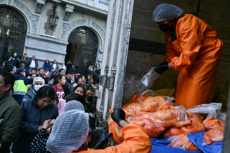 Un employé vend des poulets à des personnes faisant la queue au milieu des pénuries alimentaires provoquées par les barrages routiers, à La Paz, le 3 juin 2026 ( AFP / Marvin RECINOS )