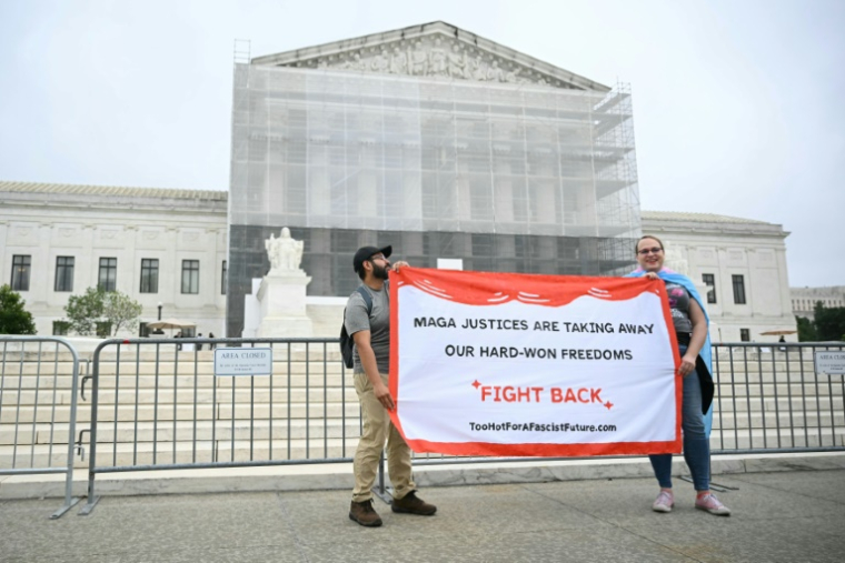 Des manifestants brandissent une banderole devant la Cour suprême américaine, après que celle-ci a limité le pouvoir des juges de bloquer à l'échelle nationale les décisions de l'exécutif qu'ils considèrent comme illégales, le 27 juin 2025 à Washington ( AFP / Mandel NGAN )