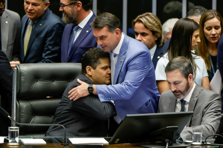 Accolade entre le sénateur Flavio Bolsonaro (d) et le président du Sénat, David Alcolumbre, à l'issue d'une session du Congrès national qui a annulé le veto du président Lula sur un projet de loi réduisant les peines des personnes reconnues coupables de tentative de coup d'État du 8 janvier 2023, le 30 avril 2026 à Brasilia, au Brésil  ( AFP / Sergio Lima )