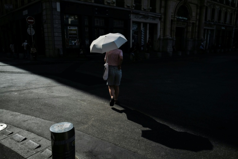 Une passante s'abrite sous une ombrelle pour se protéger du soleil à Lyon lors d'un épisode de canicule, le 24 juin 2026 ( AFP / OLIVIER CHASSIGNOLE )