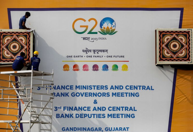 Des travailleurs installent un panneau d'affichage du G20 près du lieu d'une réunion de l'organisation à Gandhinagar, en Inde