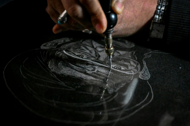 L'artiste Sadiq Poya grave le portrait d'une personne décédée sur une pierre tombale à Quetta, au Pakistan, le 17 février 2026 ( AFP / Banaras KHAN )