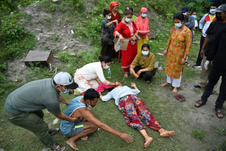 Des proches réconfortent Monac Khadka (4e à partir de la gauche) et Krishna Khadka (2e à partir de la gauche) lors de la crémation de leur fils, Ayush Khadka, à la suite de crues soudaines, dans le district de Chitwan, au Népal, le 31 août 2026 ( AFP / Prakash MATHEMA )