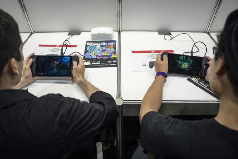 Des visiteurs jouent à "Hades 2", un jeu indépendant pour la Switch 2 de Nintendo au salon BitSummit du jeu vidéo indépendant à Kyoto, le 18 juillet 2025 au Japon ( AFP / Yuichi YAMAZAKI )