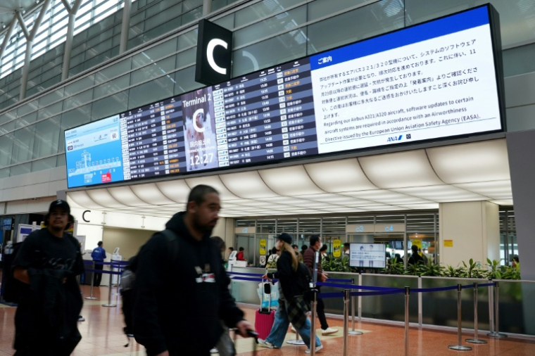 Un écran dans le hall d'enregistrement de la compagnie All Nippon Airways (ANA) indique qu'une mise à jour logicielle est nécessaire pour les appareils Airbus A321/A320 de la compagnie, entraînant des retards et des annulations de vols à l'aéroport de Haneda, le 29 novembre 2025 à Tokyo ( AFP / Kazuhiro NOGI )
