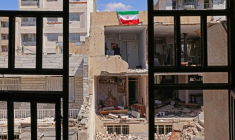 Un drapeau iranien sur le pan de mur d'un immeuble résidentiel endommagé par de récentes frappes à Karaj, au sud-ouest de Téhéran, le 3 avril 2026  ( AFP / ATTA KENARE )