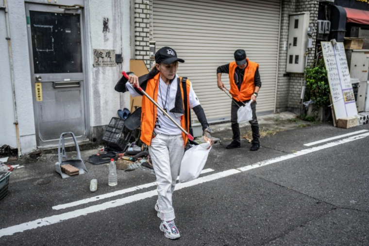 Mako Nishimura (g), yakuza à la retraite, collecte des déchets avec des anciens délinquants lors de leur opération mensuelle de ramassage de déchets à Gifu, le 28 septembre 2025 au Japon Japan's drug rings, illicit gambling dens and sex trade. An intensifying police crackdown has shrunk yakuza forces nationwide, with their numbers dipping below 20,000 in 2024 for the first time since records began in 1958. ( AFP / Yuichi YAMAZAKI )