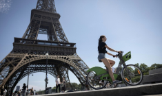 Une femme passe en vélo électrique devant la tour Eiffel, le 10 juillet 2026 à Paris   ( AFP / Behrouz MEHRI )