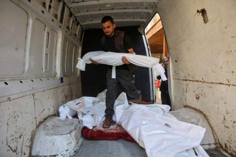 Un Palestinien transporte le corps d’un enfant dans une camionnette contenant les dépouilles d'autres personnes tuées lors de frappes aériennes israéliennes, dans l’enceinte de l’hôpital Al-Ahli Arab de Gaza-Ville, le 21 mai 2025 ( AFP / Omar AL-QATTAA )
