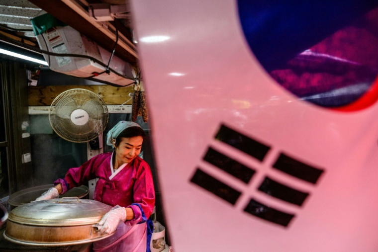 Une femme avec un cuiseur vapeur rempli de raviolis mandu à la nord-coréenne dans son magasin d'alimentation situé sur l'île de Gyodong, à environ deux kilomètres de la Corée du Nord, le 7 octobre 2025 ( AFP / ANTHONY WALLACE )
