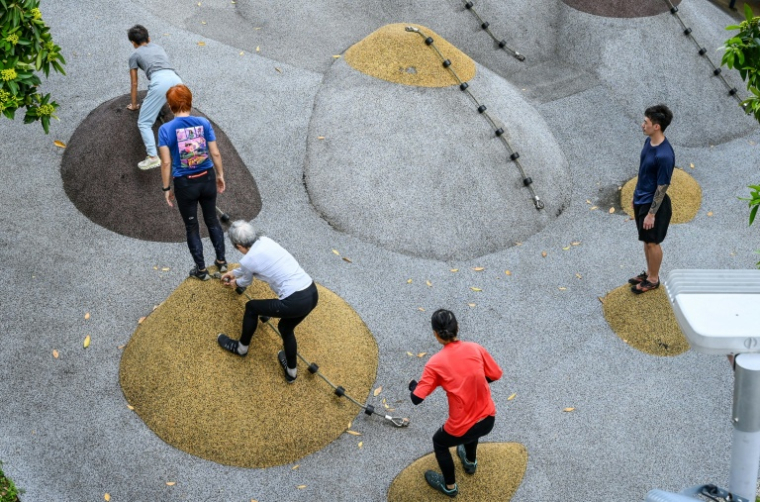 Le coach Tan Shie Boon (d) guide des personnes âgées lors d'une séance d'entraînement de parkour à Singapour, le 17 mars 2026 ( AFP / Roslan RAHMAN )