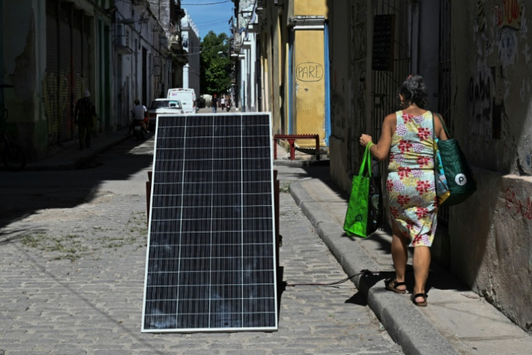 Une personne passe à côté d'un panneau solaire à La Havane pendant une coupure d'électricité générale, le 6 juillet 2026 ( AFP / YAMIL LAGE )