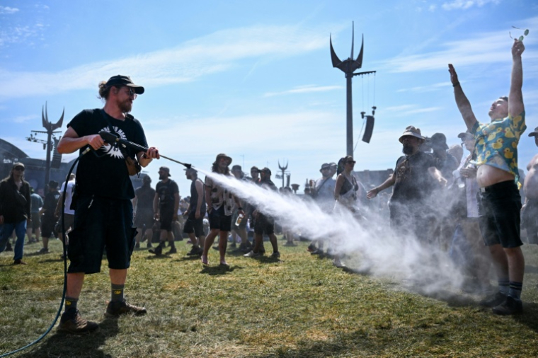 Un membre de l'organisation du Hellfest asperge d'eau des festivaliers durant une vague de chaleur lors de la 19e édition de ce festival de heavy metal à Clisson, en Loire-Atlantique, le 19 juin 2026 ( AFP / Sebastien Salom-Gomis )