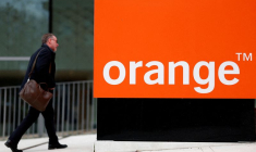 Un homme passe devant le logo de l'opérateur de télécommunications français Orange, au siège de l'entreprise à Issy-les-Moulineaux, près de Paris