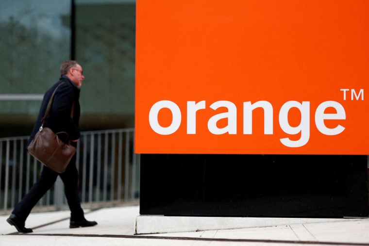 Un homme passe devant le logo de l'opérateur de télécommunications français Orange, au siège de l'entreprise à Issy-les-Moulineaux, près de Paris