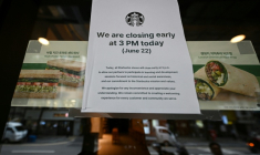 Une affiche annonçant une fermeture anticipée sur la porte d'un café Starbucks à Séoul, en Corée du Sud, le 22 juin 2026 ( AFP / Jade GAO )