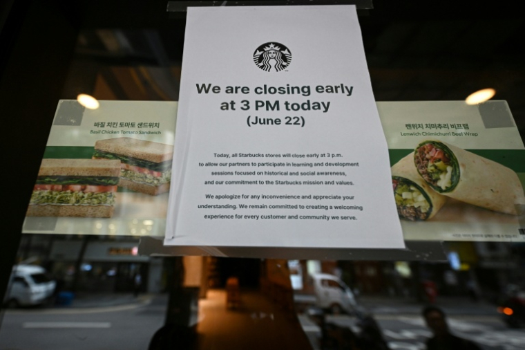 Une affiche annonçant une fermeture anticipée sur la porte d'un café Starbucks à Séoul, en Corée du Sud, le 22 juin 2026 ( AFP / Jade GAO )