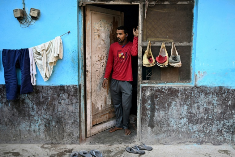 Un travailleur migrant pose devant l'entrée de son logement à Delhi, le 9 avril 2026 ( AFP / Sajjad HUSSAIN )