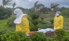 Des membres du personnel soignant en combinaison de protection transportent un patient à Rwampara après qu'un hôpital a été incendié par des manifestants qui s'étaient vu refuser l'accès aux corps de leurs proches décédés du virus Ebola, le 21 mai 2026 en RDCroups. ( AFP / Seros MUYISA )