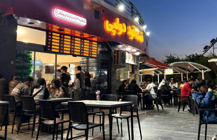 Des Iraniens attablés sur la terrasse d'un café, près du lac Chitgar, dans le nord de Téhéran, le 26 avril 2026 ( AFP / ATTA KENARE )