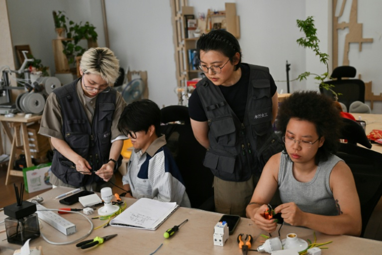 Les formatrices Wu Shuang (c) et Wang Risun (g) donnent un cours d'électricité à des participantes de l'atelier Mulan Build à Hangzhou, dans la province du Zhejiang, le 28 juin 2026 dans l'est de la Chine ( AFP / Pedro PARDO )