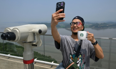 Un touriste prend un selfie avec une tasse Starbucks devant la Corée du Nord depuis une plate-forme d'observation sud-coréenne située à l'Écoparc de la Paix d'Aegibong, à Gimpo, le 1er juillet 2026  ( AFP / Jung Yeon-je )