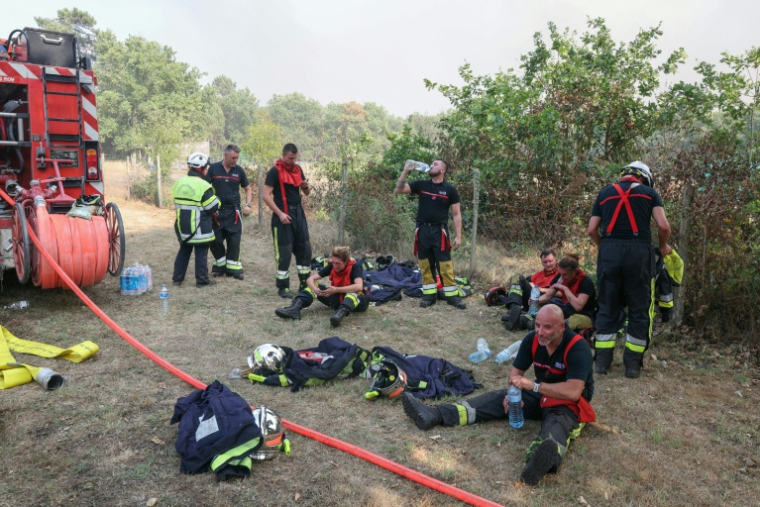 Des pompiers se reposent avec des bouteilles d'eau pendant une pause au cours des opérations de lutte contre un incendie de forêt près de Lanton, dans le sud-ouest de la France, le 29 juillet 2026 ( AFP / ALAIN JOCARD )