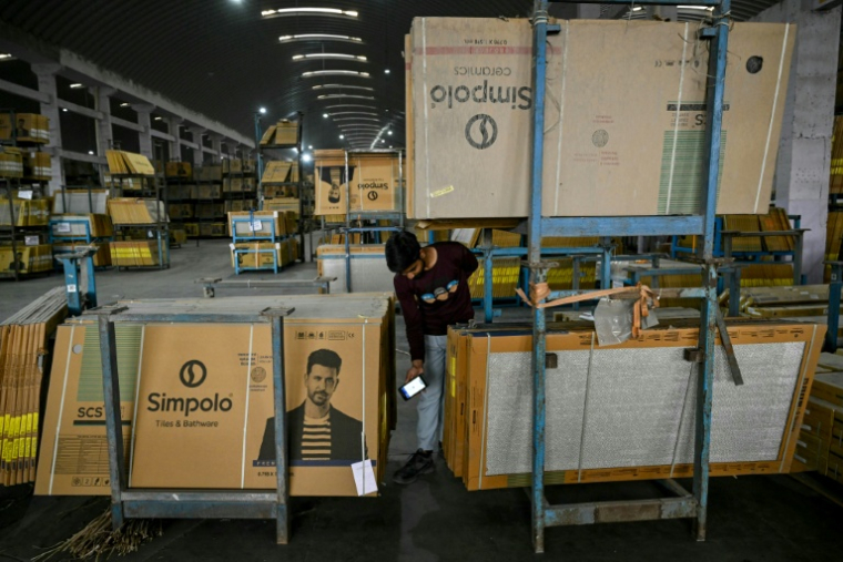Un ouvrier scanne des carreaux de céramique emballés avant leur livraison dans une usine confrontée à des difficultés d'approvisionnement en gaz, le 26 mars 2026 à Morbi, en Inde ( AFP / Indranil MUKHERJEE )