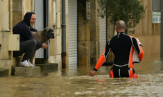 Un homme assis sur le seuil de sa maison, entourée d'eau, discute avec un pompier dans le centre-ville inondé par la Garonne, le 16 février 2026 ( AFP / Gaizka IROZ )