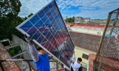 Une équipe de techniciens de systèmes photovoltaïques hisse des panneaux sur le toit d'une cantine pour personnes âgées géré par l’Eglise catholique, dans le quartier de Guanabacoa à La Havane, le 4 février 2026 ( AFP / ADALBERTO ROQUE )
