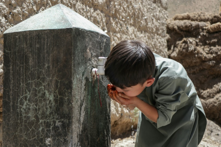 Un enfant afghan issu de la communauté hazara se désaltère dans le village de Qavariyak, dans la province centrale de Bamiyan, le 18 juin 2025 ( AFP / Mohammad Faisal NAWEED )