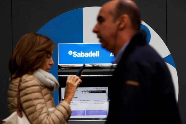 Des passants devant une agence de la banque Sabadell à Madrid