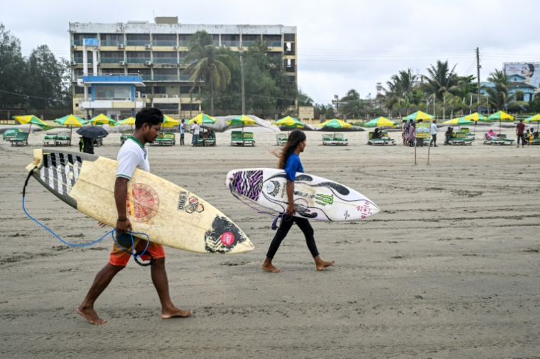 Les surfeurs Mohammad Mannan et Fatima Akhter sur la plage de Cox's Bazar, dans le sud-est du Bangladesh, le 22 juin 2026   ( AFP / Munir UZ ZAMAN )