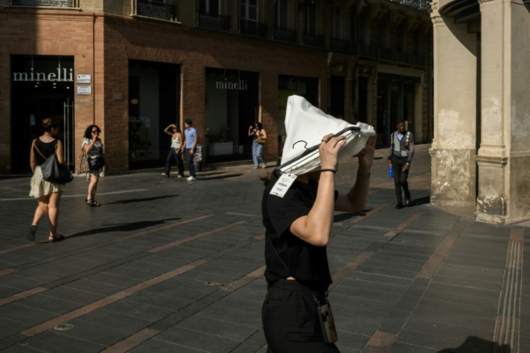 Une femme se protège du soleil avec un vêtement le 1er juillet 2025 à Toulouse lors d'une vague de chaleur ( AFP / Ed JONES )