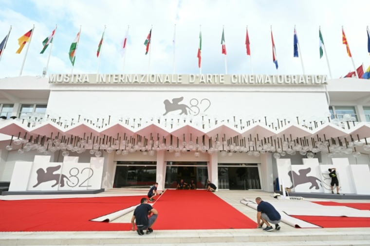 Des ouvriers intallent le tapis rouge à la veille de l'ouverture de la 82e Mostra de Venise, le 26 août 2025 ( AFP / Stefano RELLANDINI )
