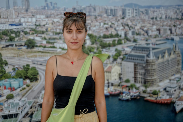 La sociologue Ayça Yüksel devant une affiche montrant la gare de Haydarpasa à Istanbul, le 22 août 2025 en Turquie ( AFP / Ozan KOSE )