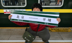 Un homme brandit une banderole "Pékin-Pyongyang" devant le train K27 à destination de Pyongyang, à la gare de Pékin, le 12 mars 2026 en Chine ( AFP / ADEK BERRY )
