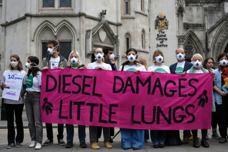 Des manifestants rassemblés devant la Haute Cour à Londres, à l'ouverture du procès de cinq géants de l'automobile impliqués dans le scandale des voitures diesel truquées, le 13 octobre 2025 ( AFP / CARLOS JASSO )