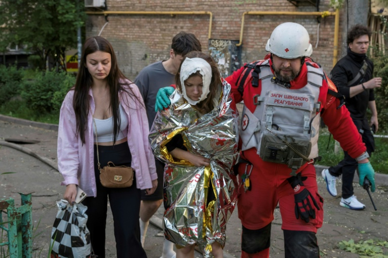 Un secouriste évacue une personne blessée dans les intenses bombardements russes nocturnes qui ont particulièrement visé la capitale ukrainienne, le 24 mai 2026 à Kiev  ( AFP / Vladyslav MUSIENKO )