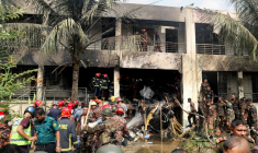 Des pompiers et des membres de la sécurité sur le site du crash d'un avion de l'armée de l'air sur une école à Dacca, le 21 juillet 2025 au Bangladesh ( AFP / Abdul Goni )