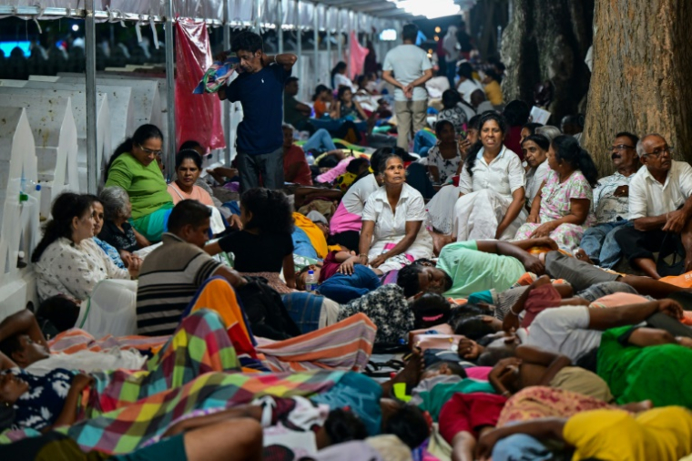 Des pèlerins campent sur le trottoir dans l'attente d'admirer une relique de Bouddha le 18 avril 2025 à Kandy au Sri Lanka ( AFP / Ishara S. KODIKARA )