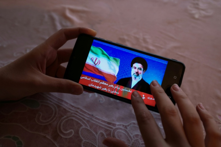 Une Iranienne regarde le premier message du nouveau guide suprême, Mojtaba Khamenei, diffusé par la télévision nationale, le 12 mars 2026 ( AFP / - )