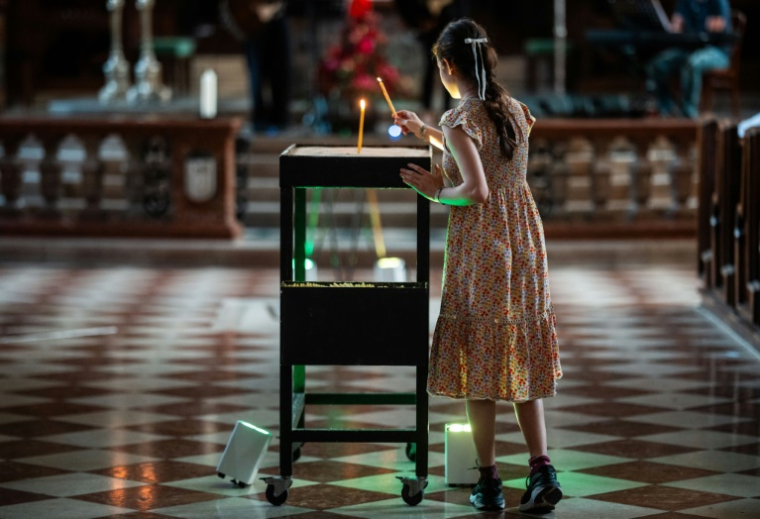 Une petite fille allume une bougie dans la cathédrale Saint-Etienne de Vienne, le 11 juin 2025, en hommage aux victimes de la tuerie scolaire survenue la veille à Graz ( APA / GEORG HOCHMUTH )
