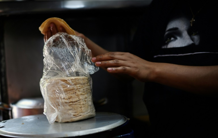 Un commerçant pèse un paquet de tortilla dans un point de vente ambulant à Mexico le 8 mai 2025 ( AFP / Alfredo ESTRELLA )