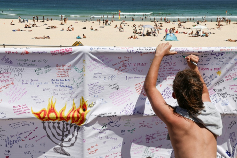 Une personne écrit un message sur une bannière près de la plage de Bondi, en Australie, le 18 décembre 2025 ( AFP / DAVID GRAY )